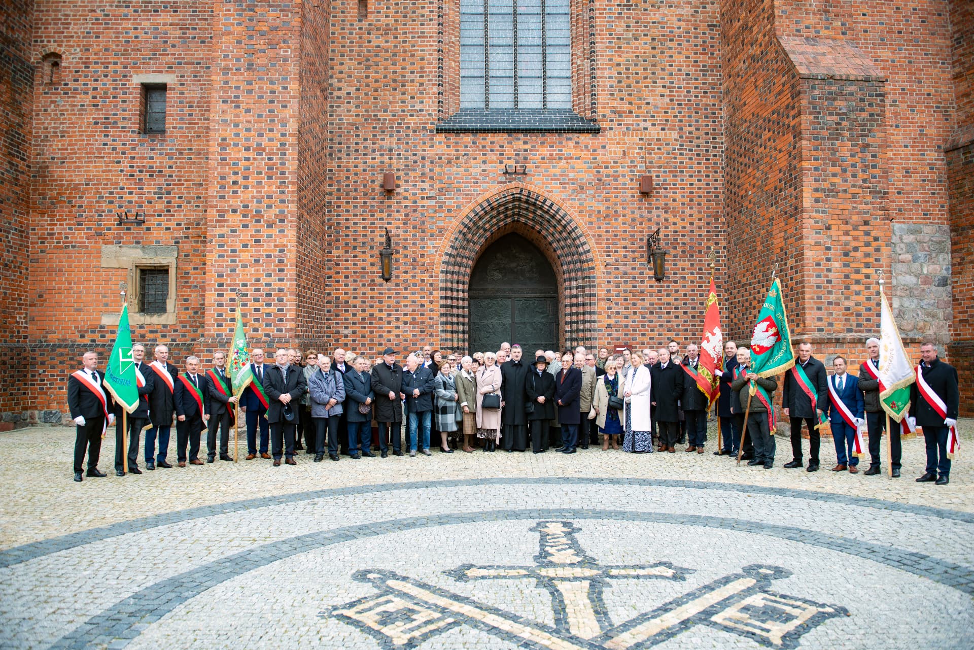 Członkowie Wielkopolskiego Związku Ogrodniczego ze sztandarami przed kościołem podczas uroczystości jubileuszowej